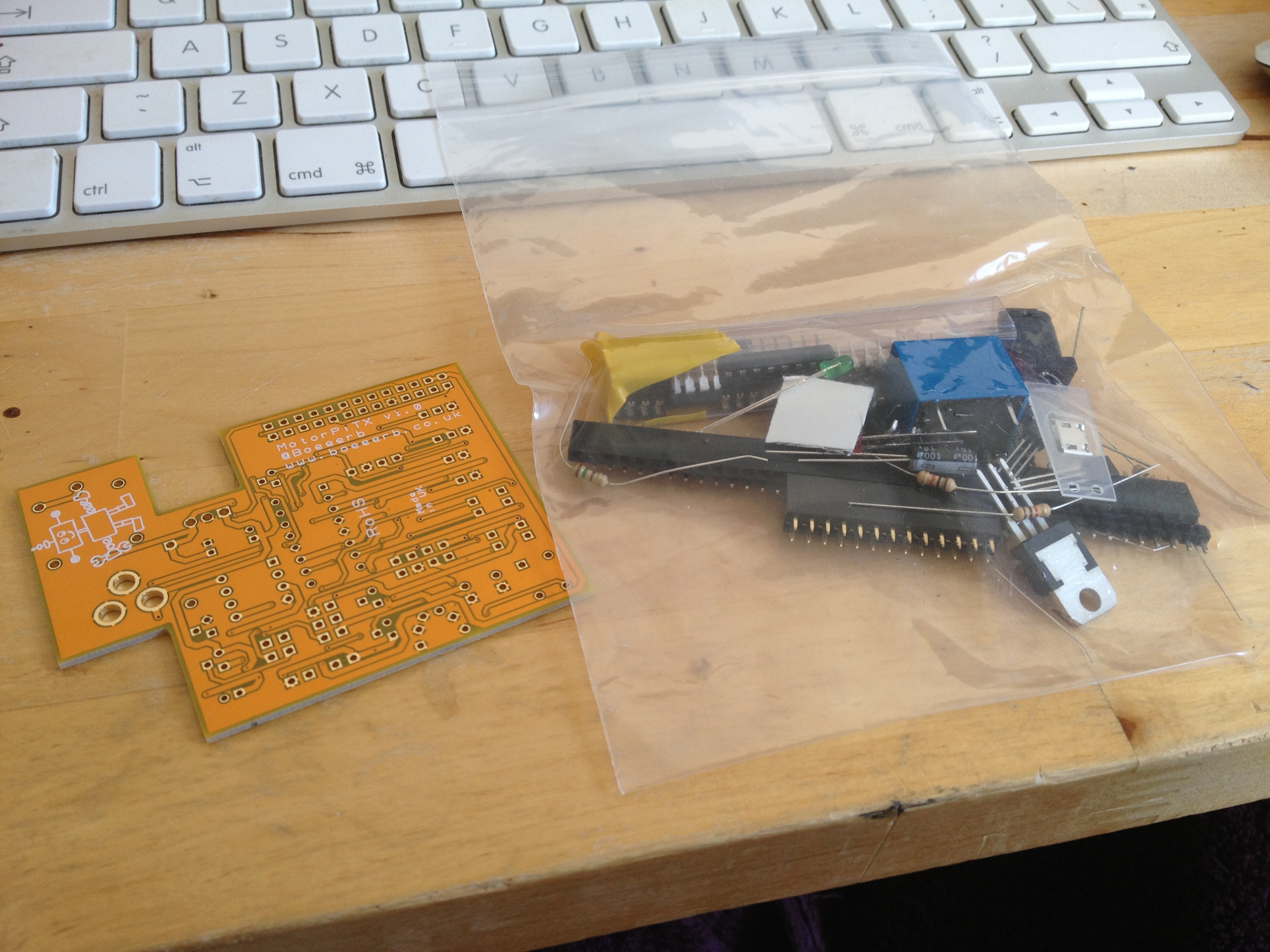 A PCB with no components on it and a bag of componenets